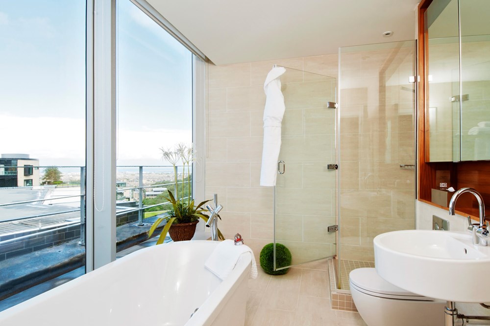 Master Suite bathroom with free standing bathtub and floor-to-ceiling windows at Apex Waterloo Place Hotel