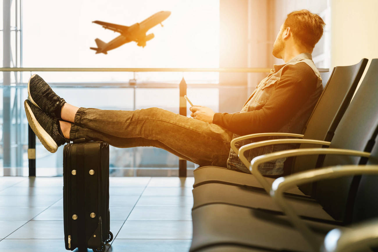 Airport delays made better with stylish luggage Man in airport watching plane take off