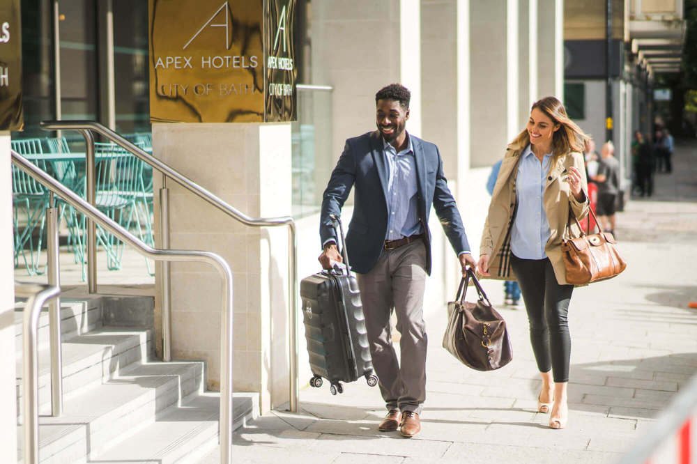 Apex concierge staff helping a guest into Apex City of Bath Hotel with her bags Apex concierge staff helping a guest into Apex City of Bath Hotel with her bags