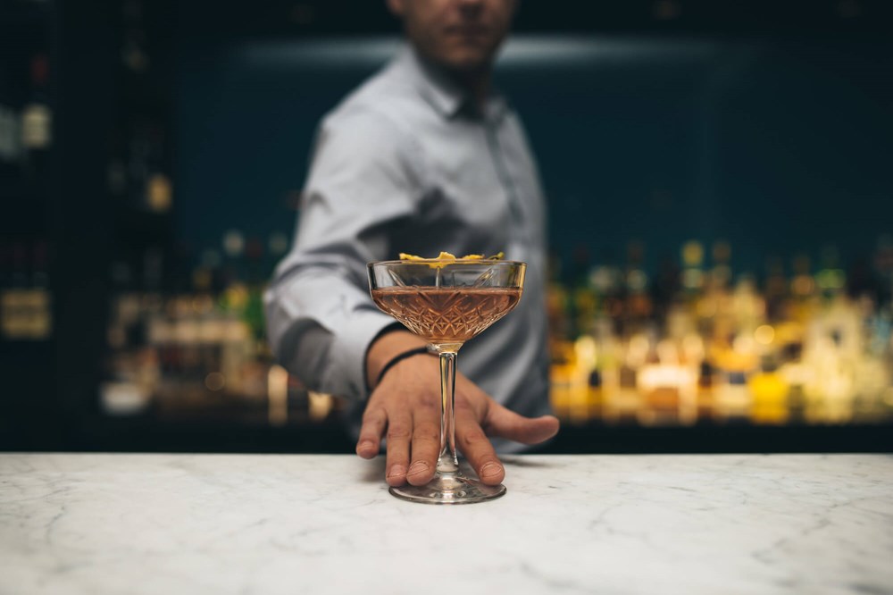 Bartender sliding cocktail across the bar