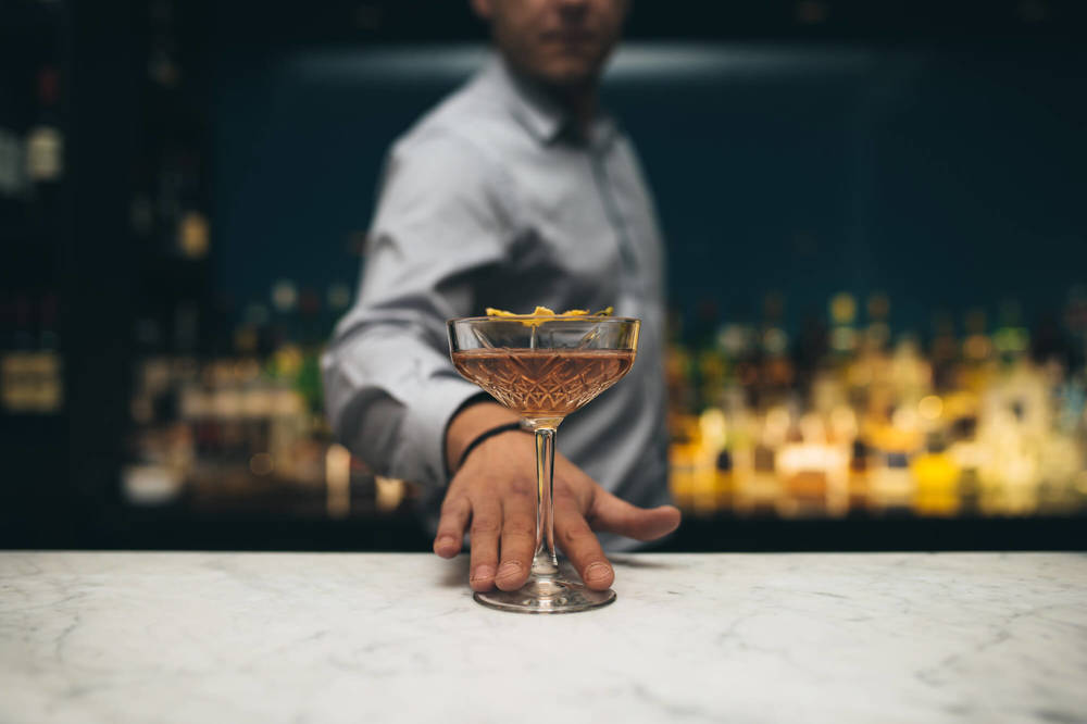 Drinks at The Lampery, Seething Lane Bartender sliding cocktail across the bar
