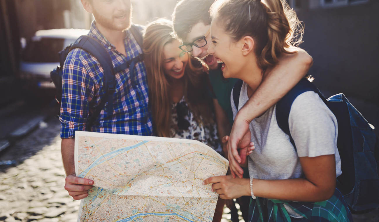 Travelling with the full family group of friends looking at map and laughing