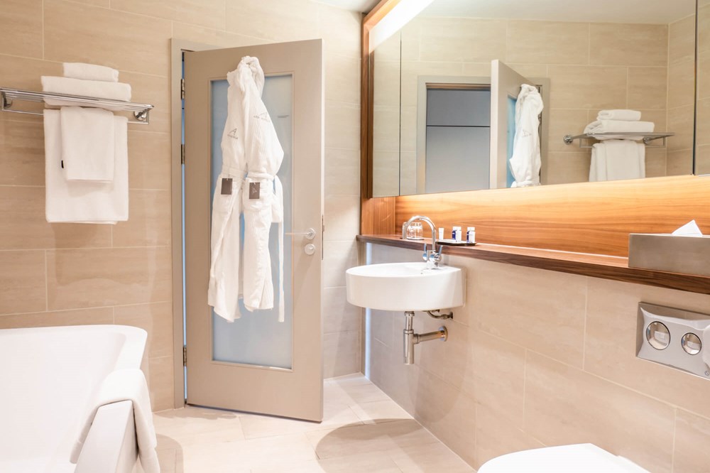 Superior Room bathroom with bath and robes hanging on the back of door at Apex Waterloo Place Hotel