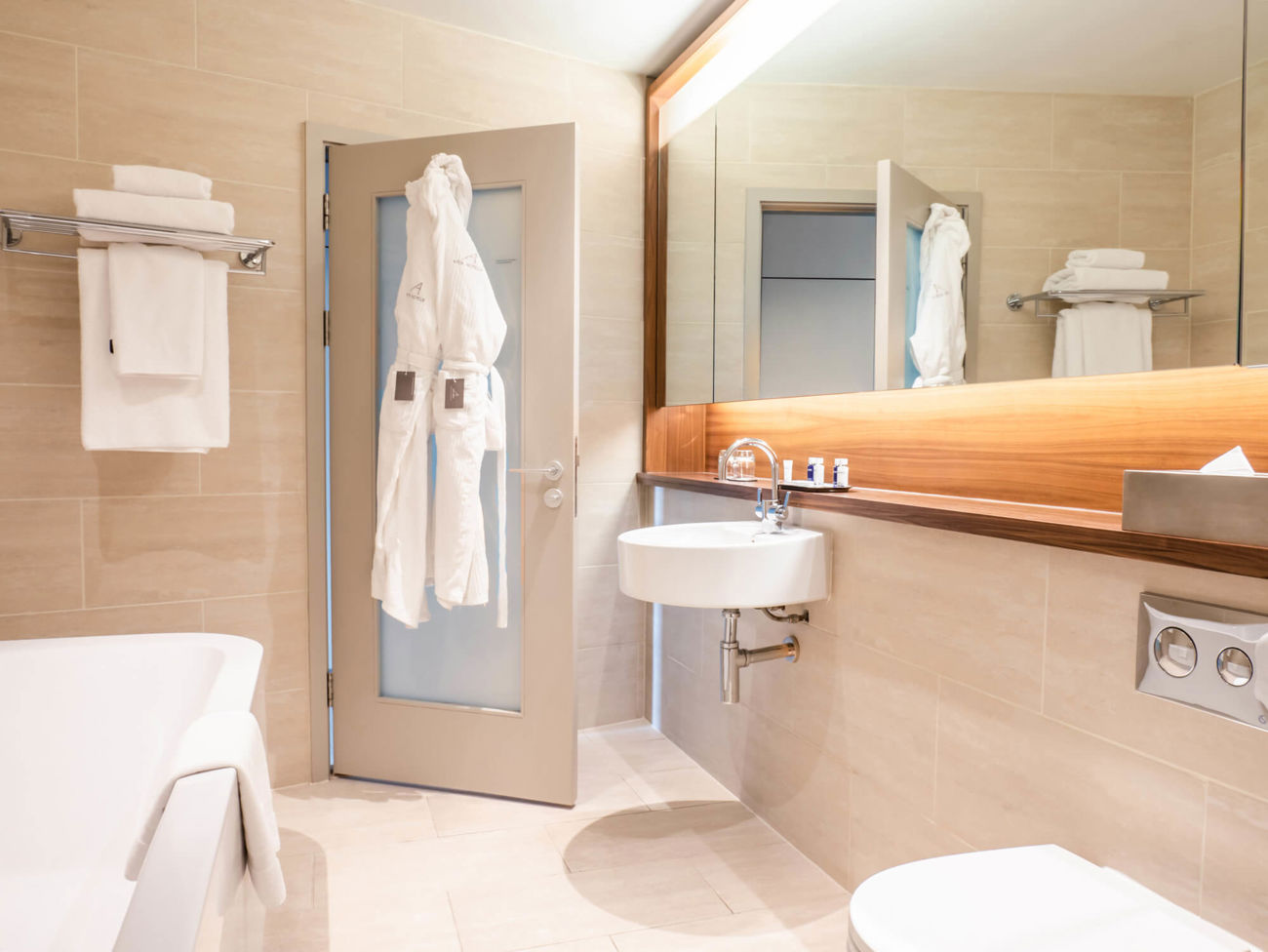 Bathroom in Superior Room at Apex Waterloo Place Hotel with bath, large mirror and robes hanging on door