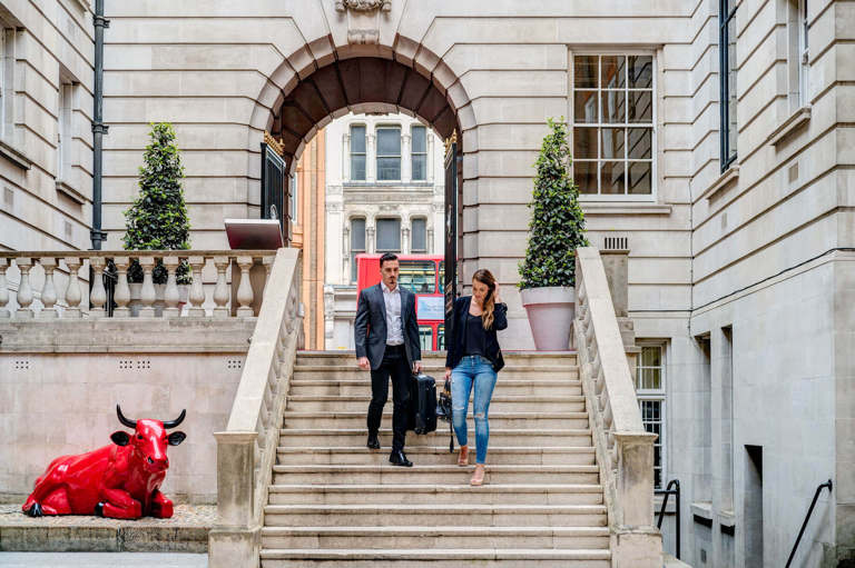 A male and female walking down the steps outside Apex Temple Court Hotel