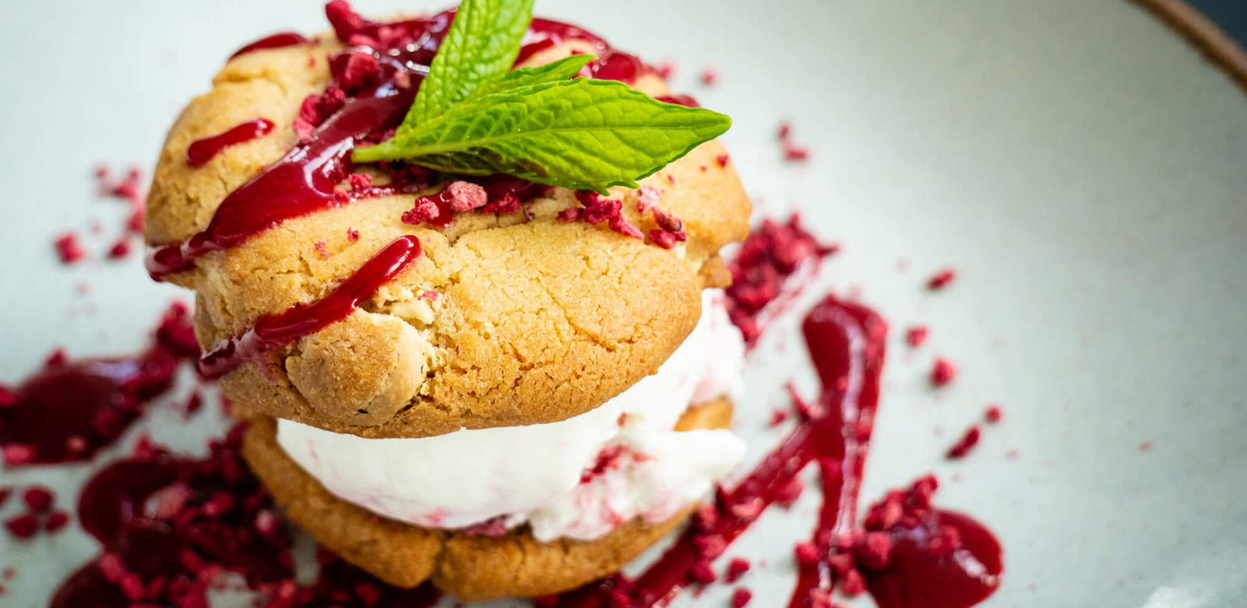 Cookie ice cream sandwich dessert with raspberry sauce Cookie ice cream sandwich dessert with raspberry sauce