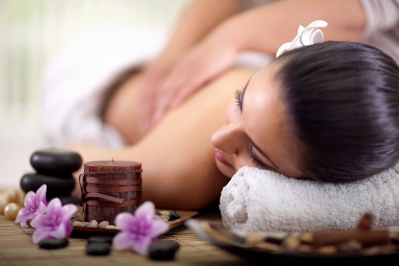 Massages at Apex Hotels Woman getting a massage with hot stones next to her