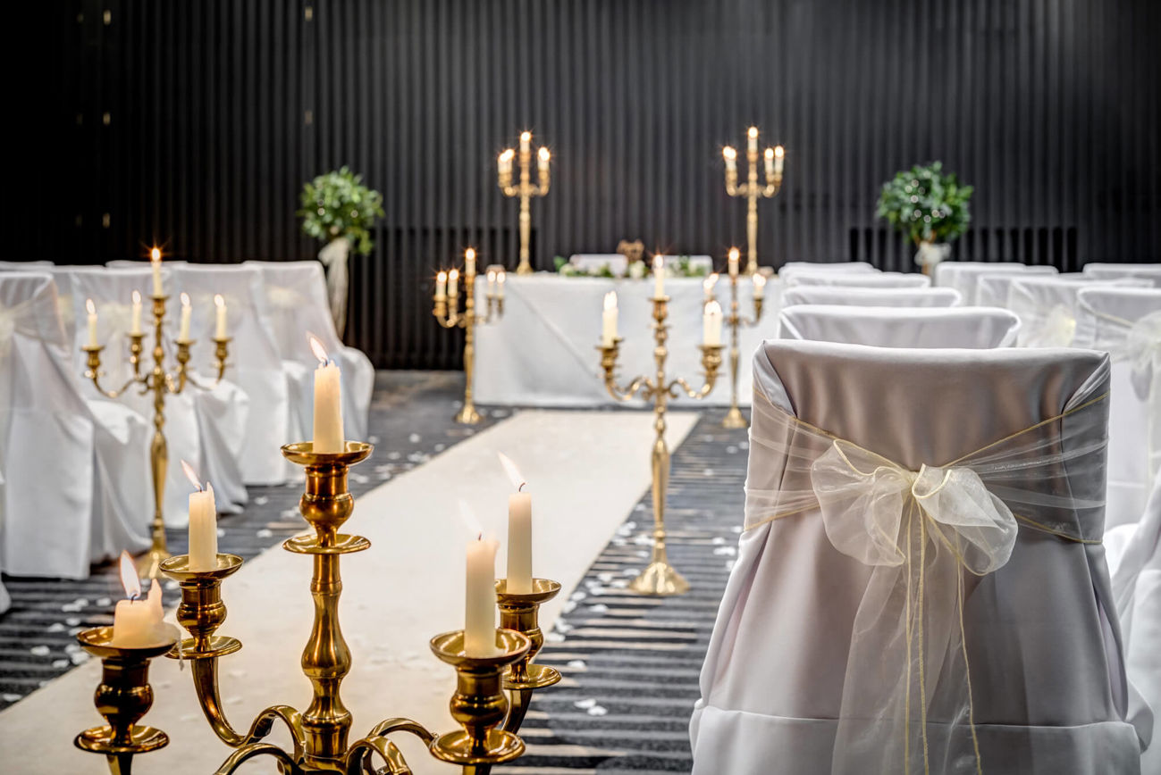 Lansdown Suite set up for wedding ceremony with white chair covers, aisle and gold candles
