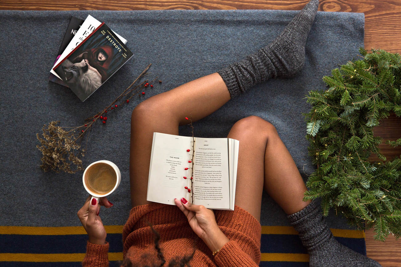Cashmere socks for travelling Person reading a book wearing fluffy socks, holding a cup of tea