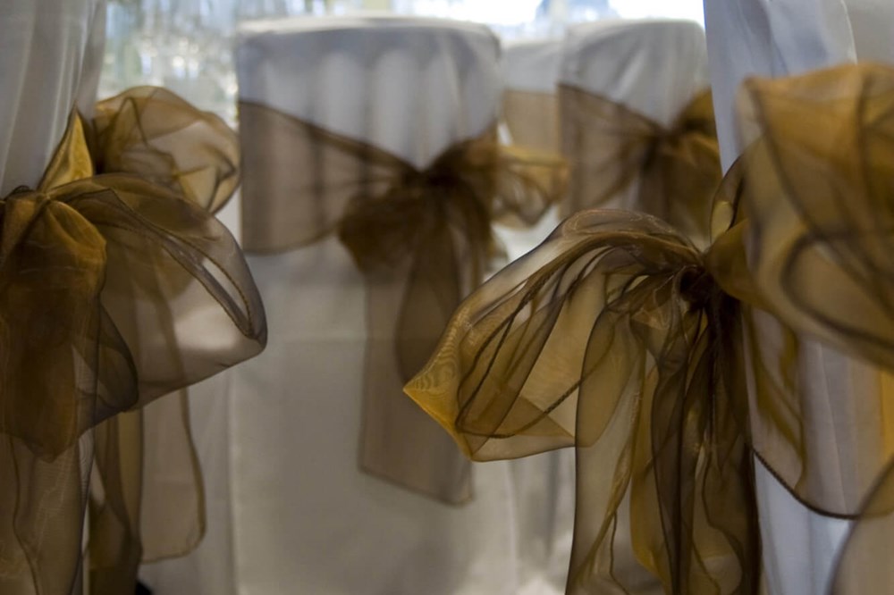 White chair covers with gold bows at Apex Waterloo Place Hotel