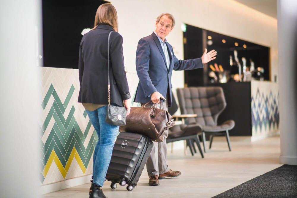 Staff member carrying guest's luggage and leading her into hotel Staff member carrying guest's luggage and leading her into hotel